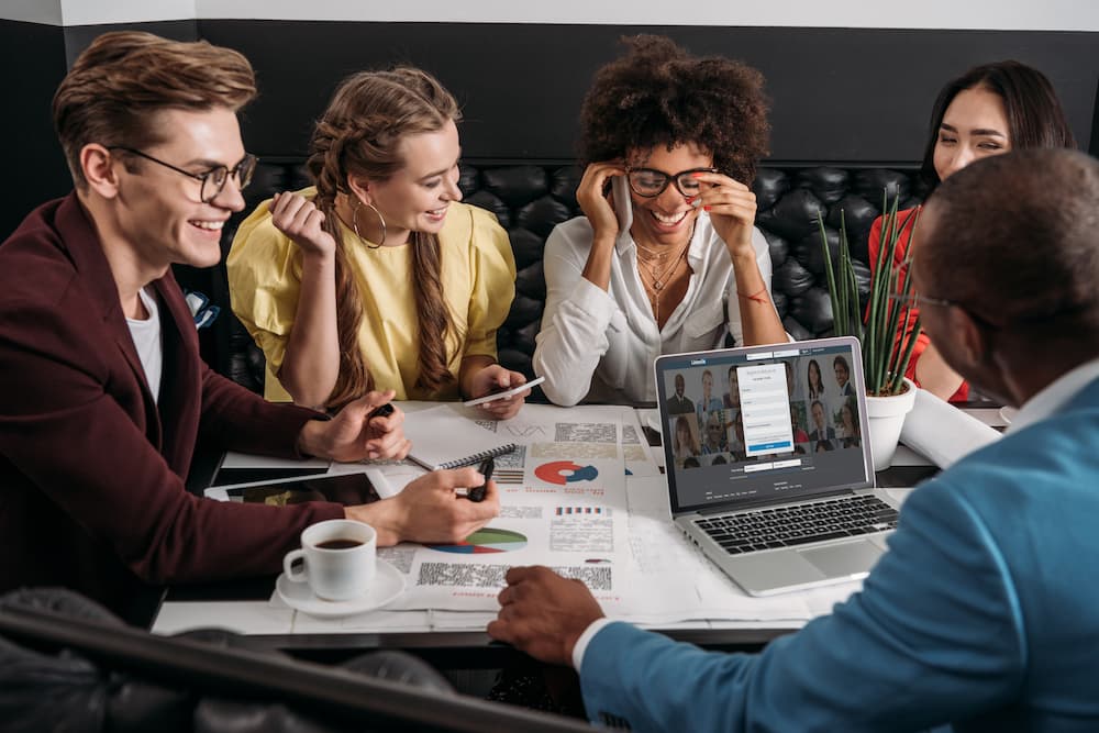 Group of professionals networking at a meeting in a restaurant using the LinkedIn app