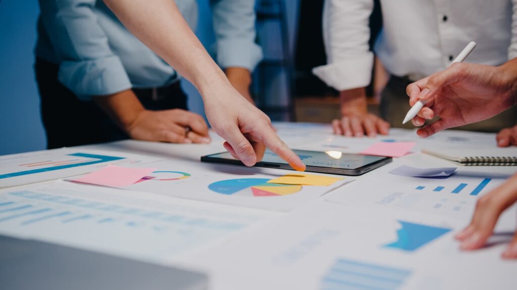 Marketing professionals at a desk designing a marketing plan with different graphs and materials