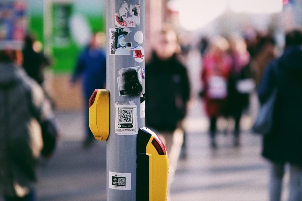 A random QR code stuck on a traffic light post in a crowded street