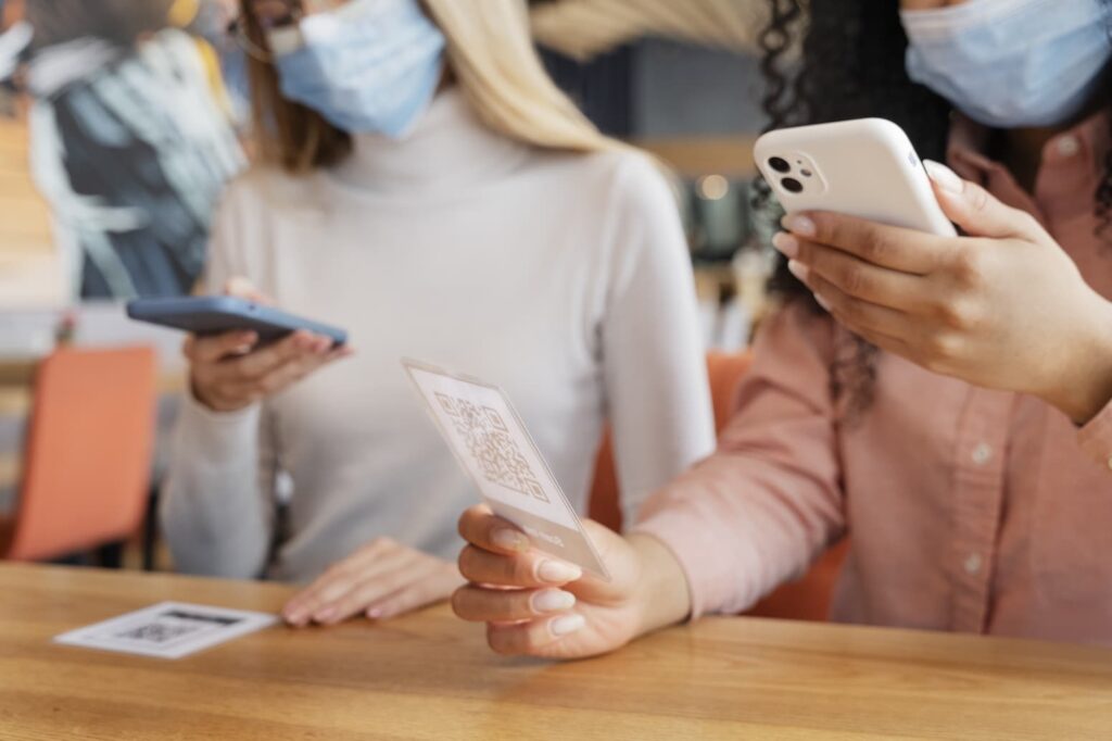 Women scanning menu QR codes at a restaurant table with their smartphone cameras